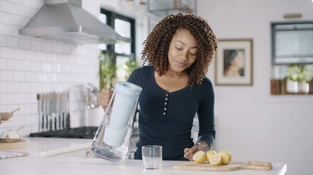 A woman using a water filter pitcher
