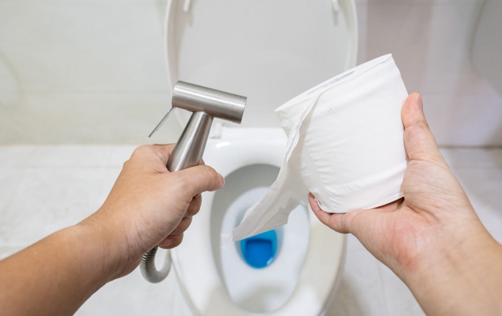 man holding bidet and toilet paper