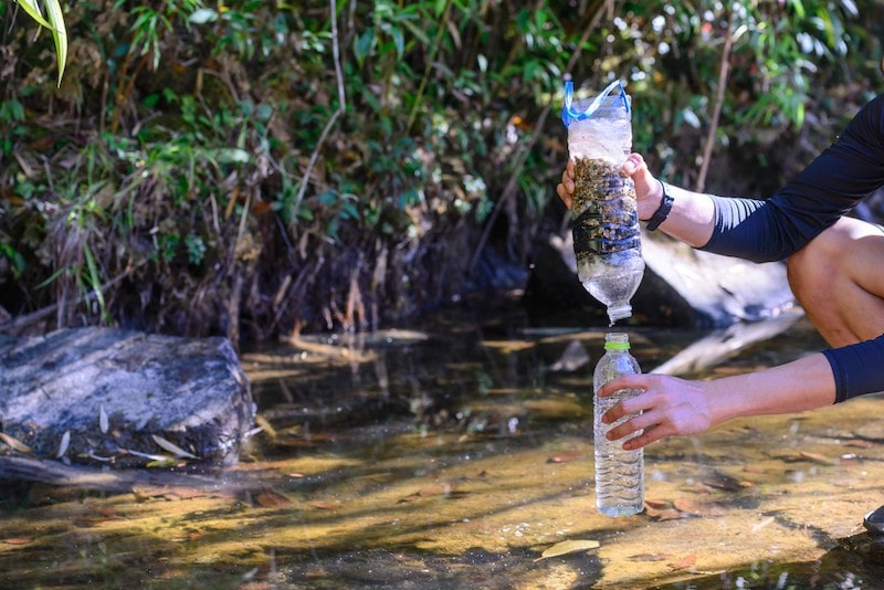 diy natural water filter outside using water bottles rocks and charcoal