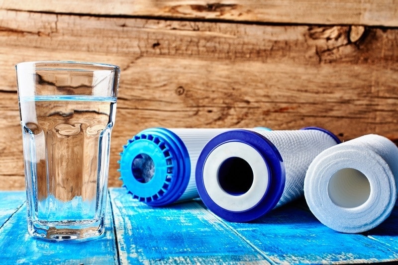 Carbon cartridges and a glass of water on a wooden background