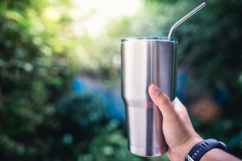 Hand holding a stainless steel tumbler_nuttadol kanperm_shutterstock