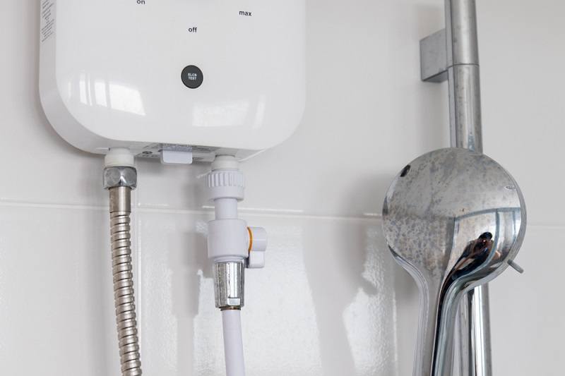 Instant tankless electric water heater installed on white tile wall