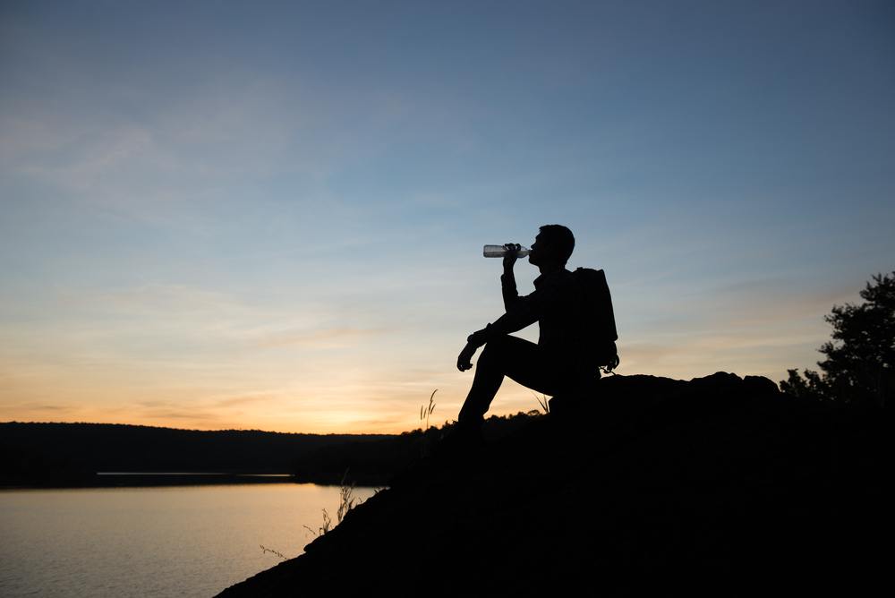 man drinking water hiking
