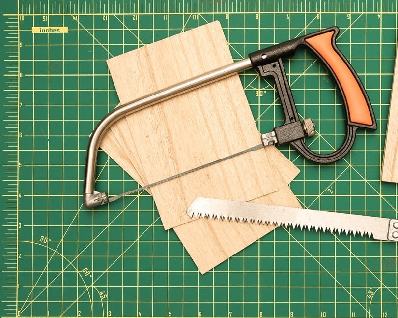 Wood saw on green cutting board with balsa wood