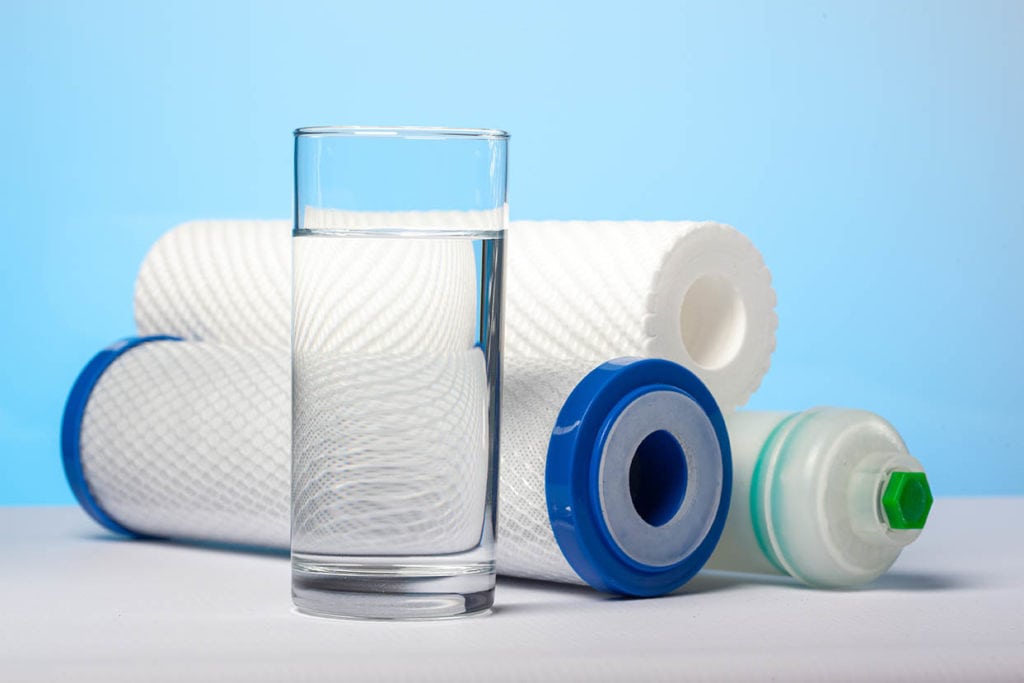 A glass of water in front of filter cartridges
