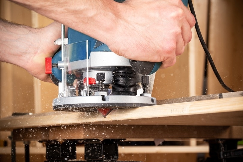 carpenter with hand wood router machine at work