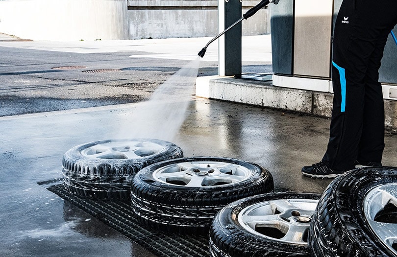 cropped man pressure washing the tires