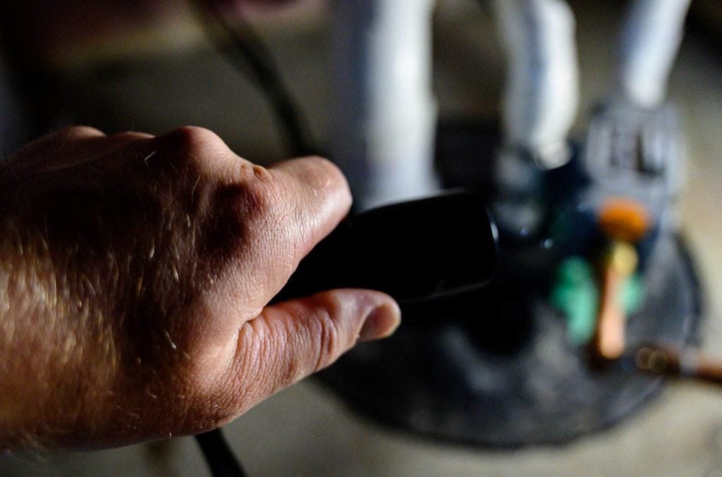 hand holding flashlight towards sump pump