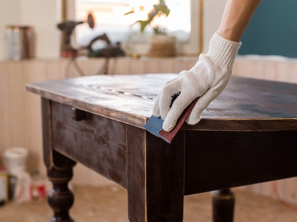 hand removing varnish on table