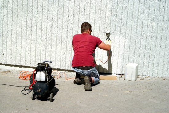 man spraying paint on wall