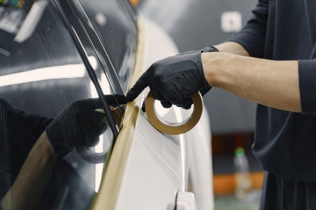 person putting masking tape in the car