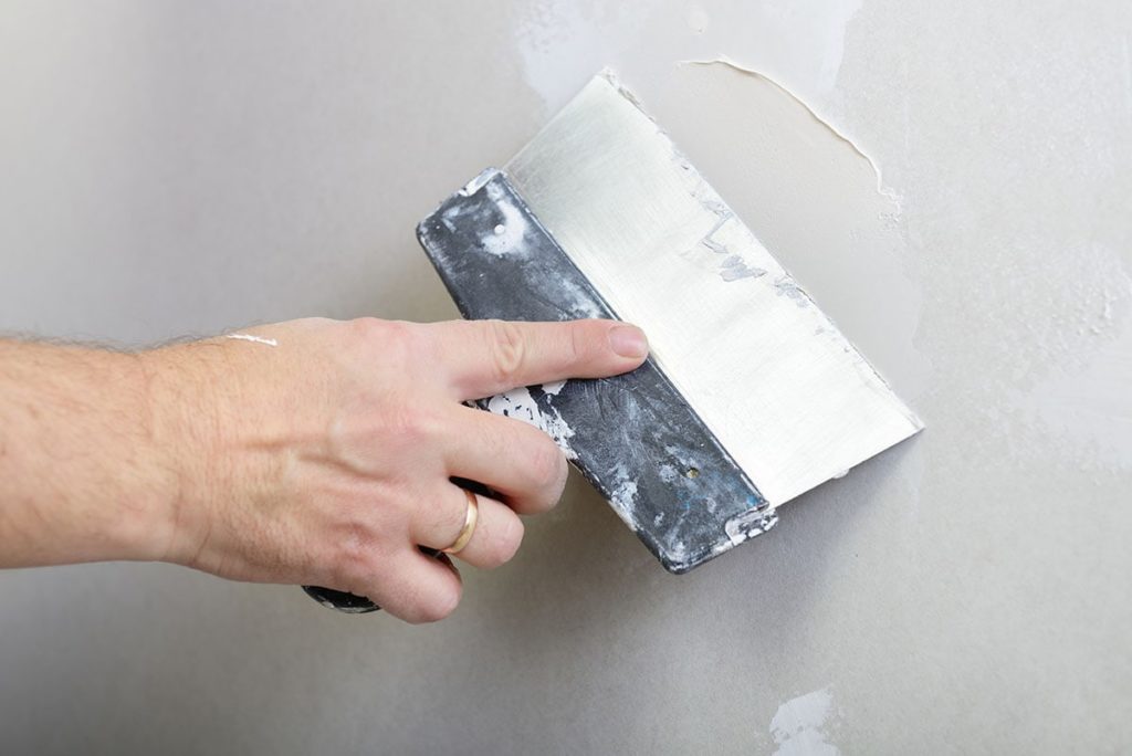 person using drywall knife