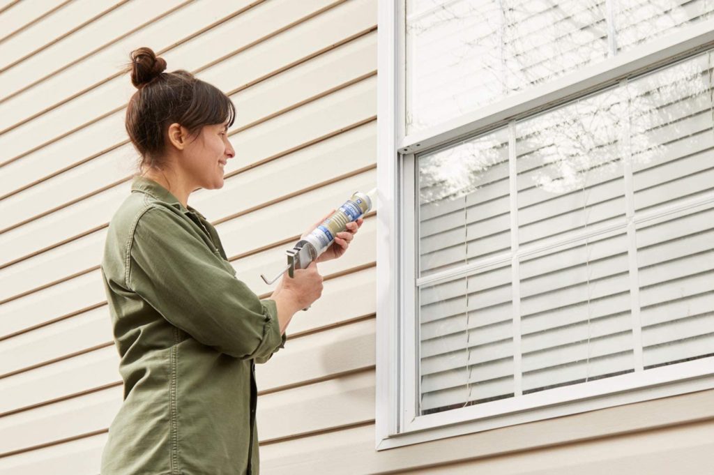 woman using GE GE500 Silicone Sealant Caulk on window