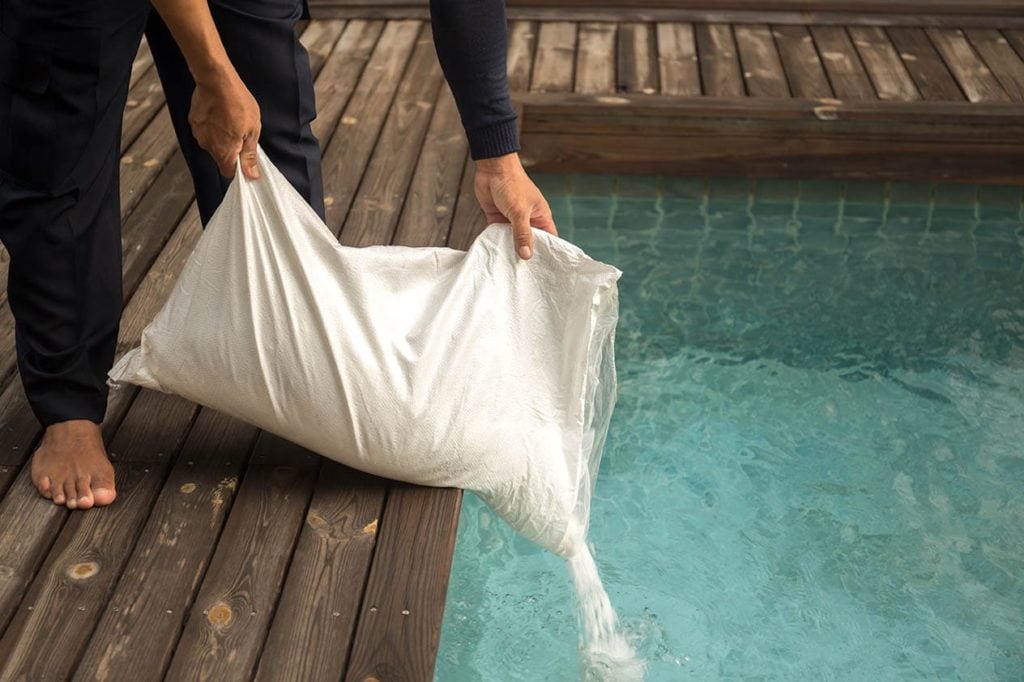 Man putting salt in the pool