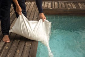 Man putting salt in the pool