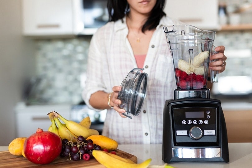 Woman making fruit smoothie in kitchen