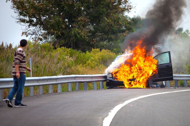 man watching car on fire on a curved road