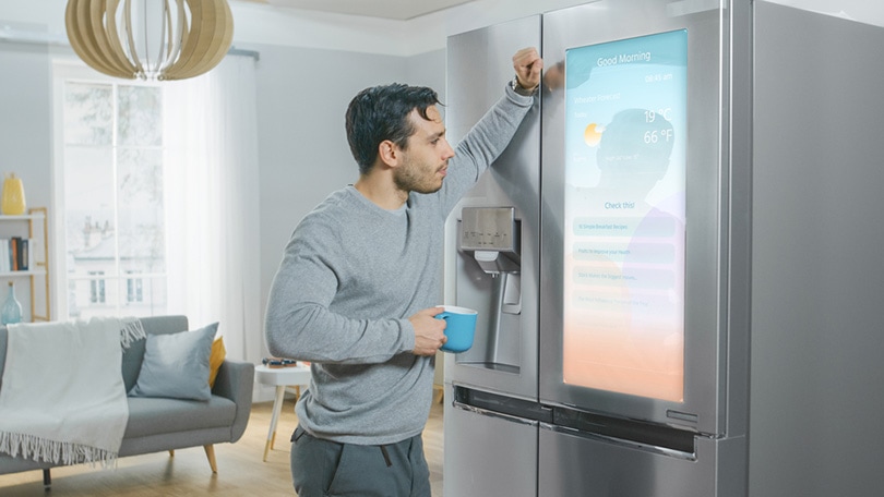 a young man standing next to a smart refrigerator