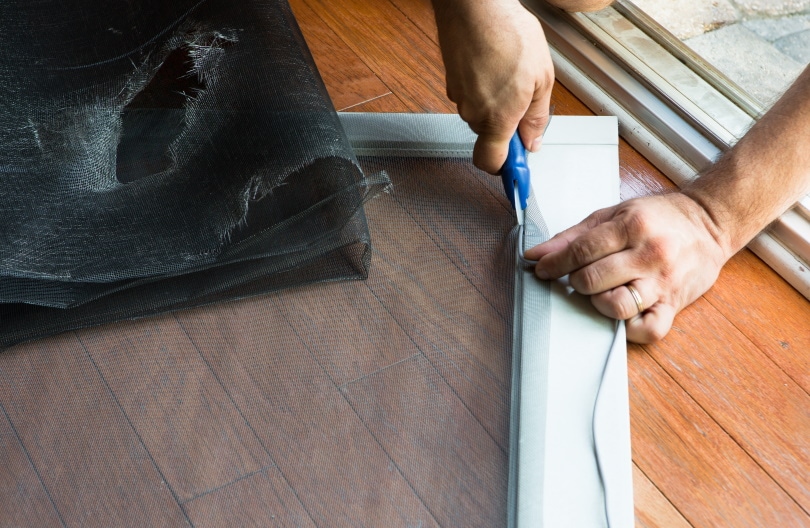 man fixing window screen