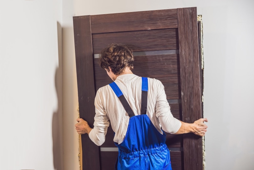 man installing new door