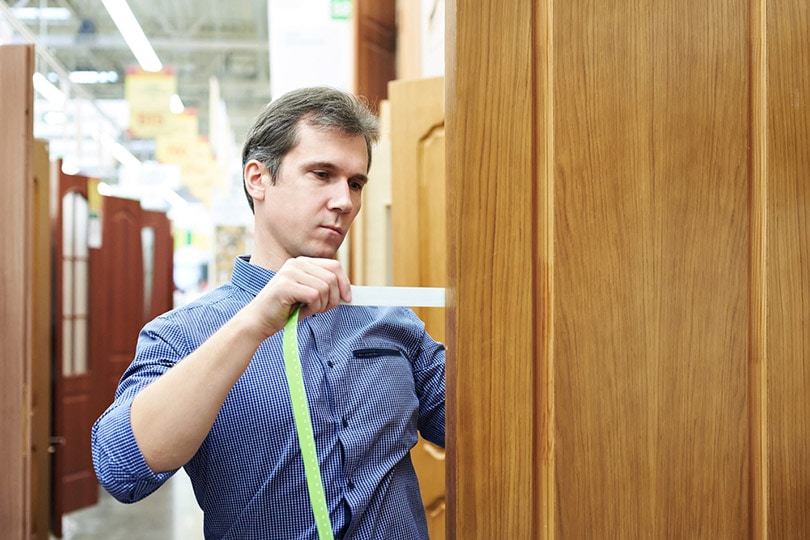 a male customer measuring the thickness of a door