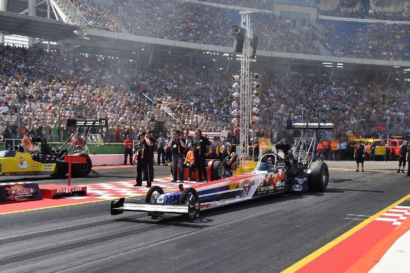 crowd cheering for a top fuel dragster in a drag race