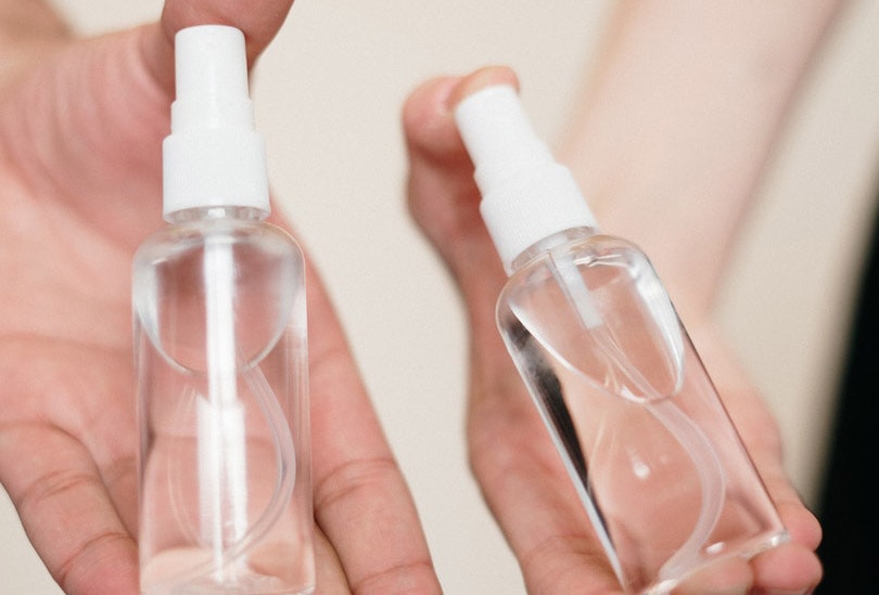 hands holding alcohol spray bottles