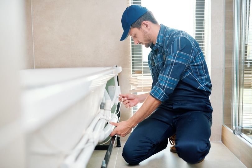 man installing pipe on bathtub
