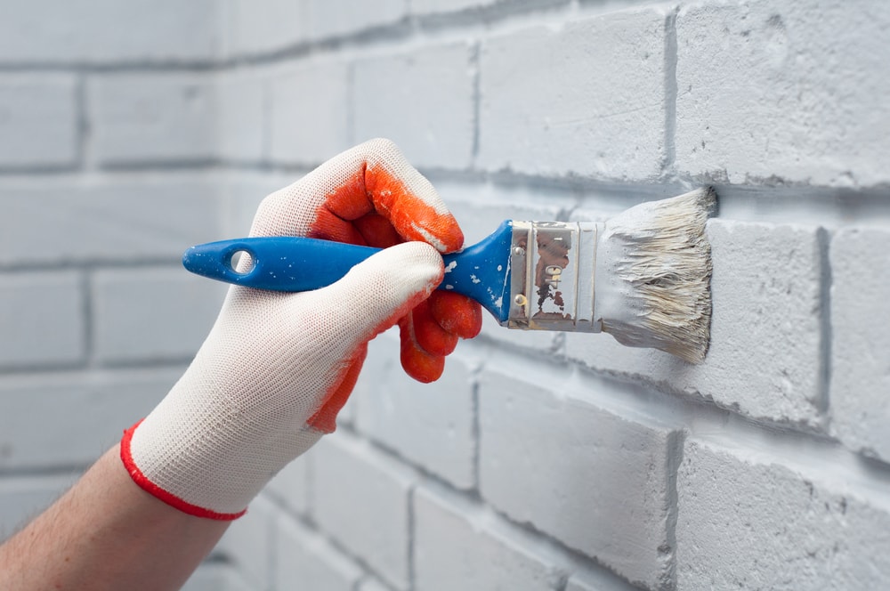 man painting brick walls white