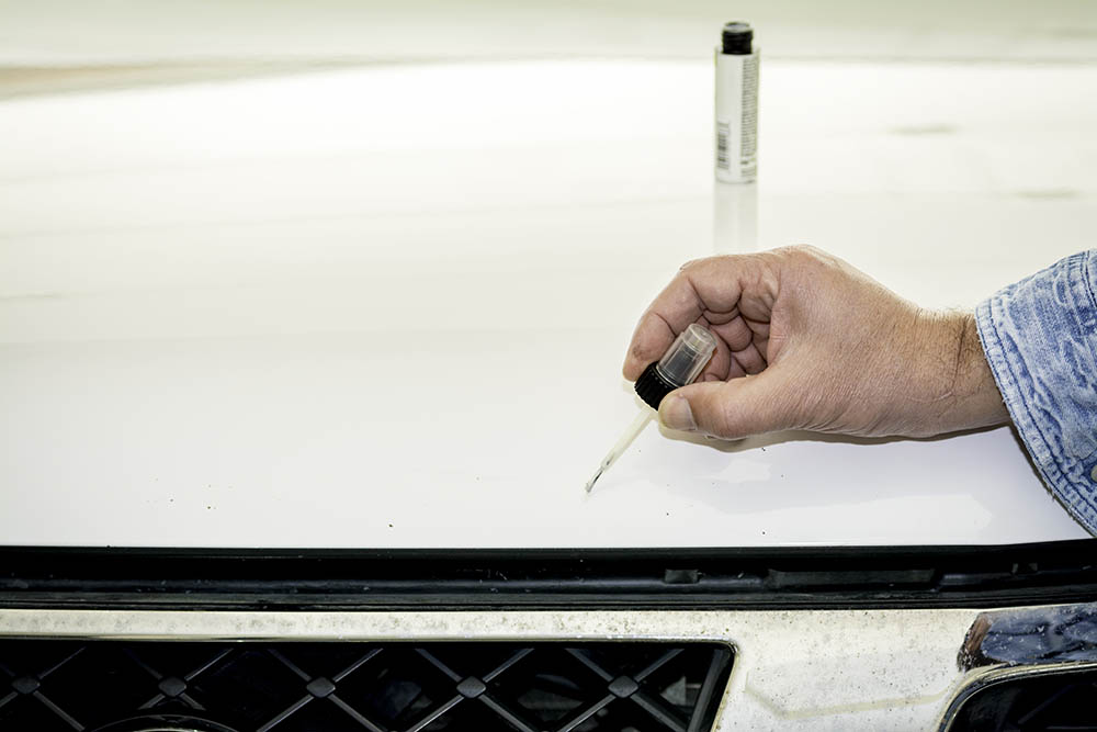 person applying touch paint on the car