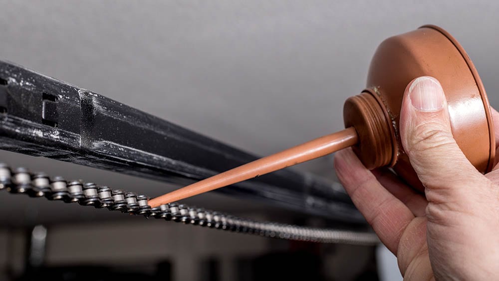 person lubricating garage door