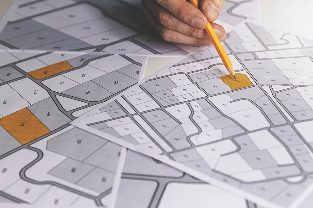 person pointing on cadastral map with pencil
