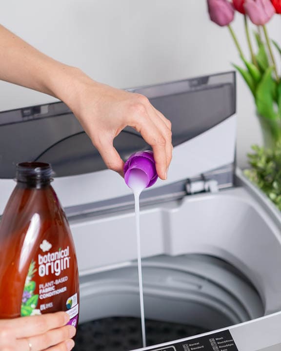 person pouring fabric conditioner in the laundry