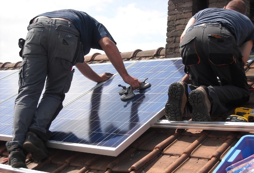 two men installing solar panels on the roof