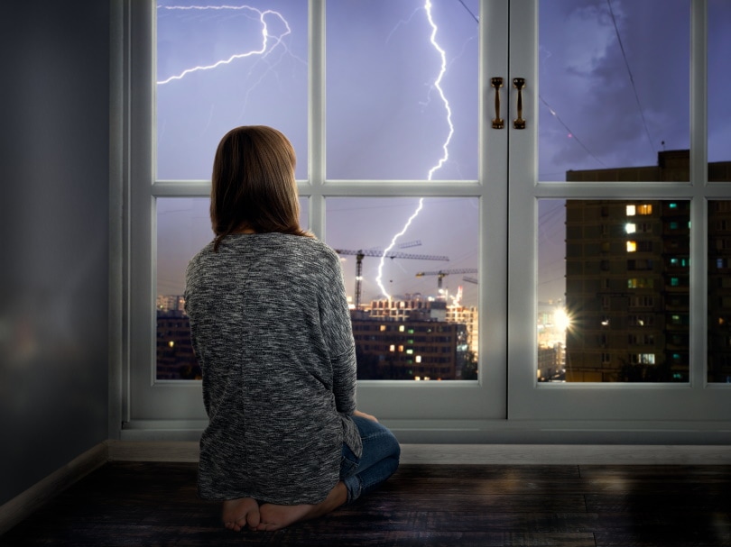 woman near window watching thunder storms