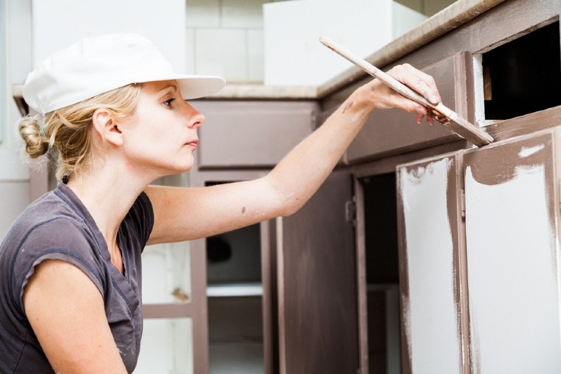 young woman painting kitchen cabinets