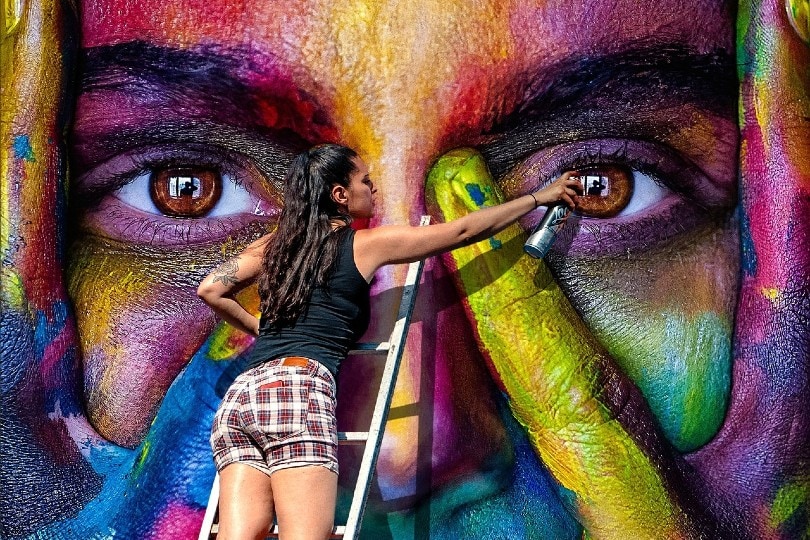 young woman using spray paint for wall art