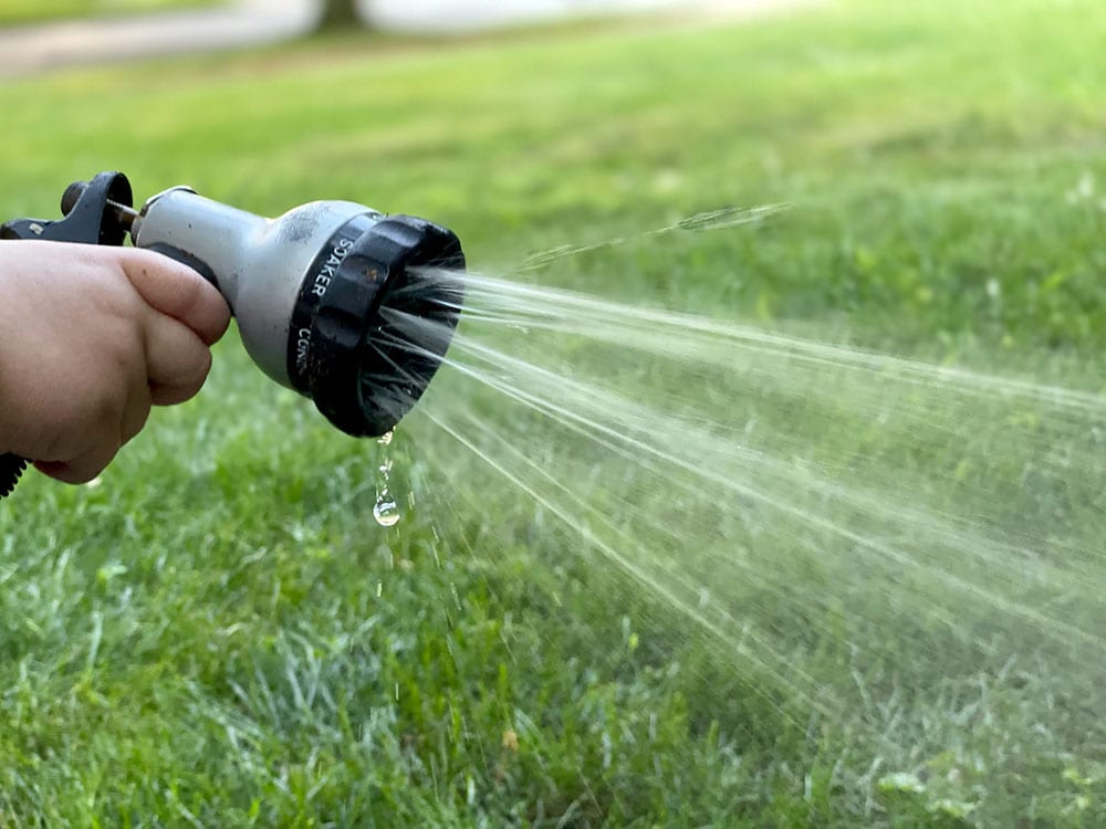 close up person using a sprinkler hose
