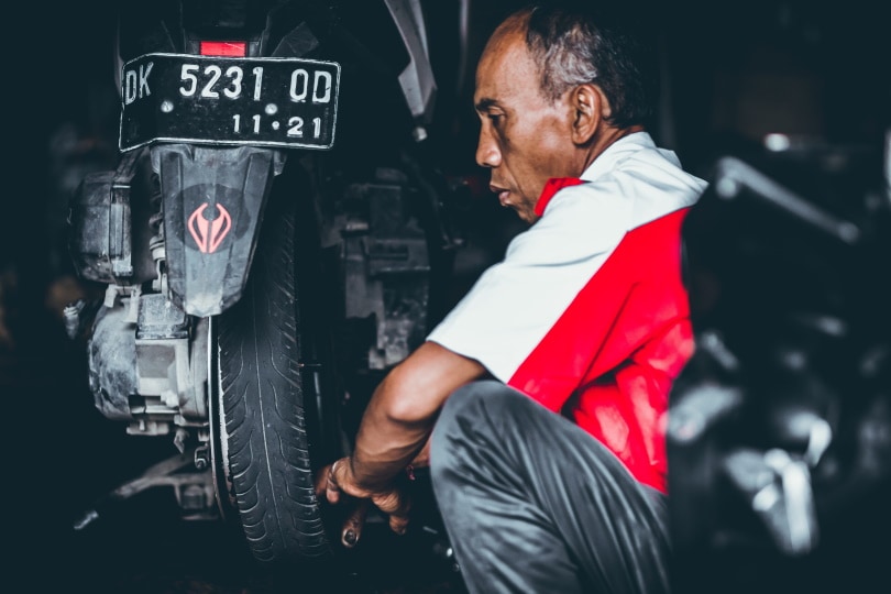 man checking motorcycle tire