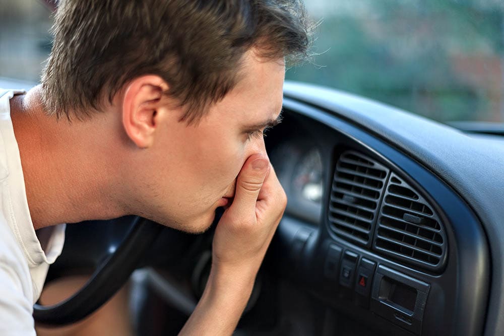 man covering his nose from bad smell in the car