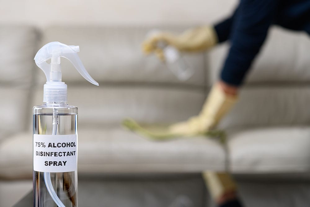 person cleaning couch using alcohol on the background