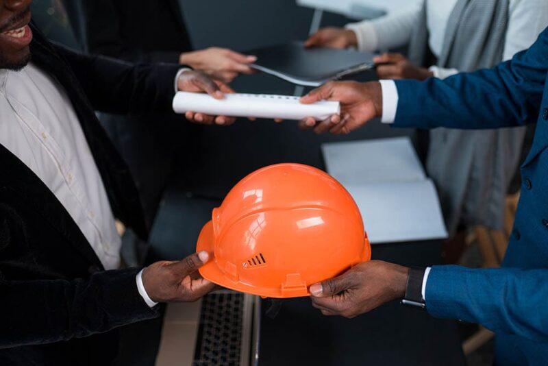 person handing over building permit and helmet