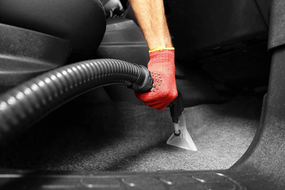 person vacuuming the car interior
