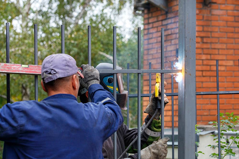 two professionals installing metal fence