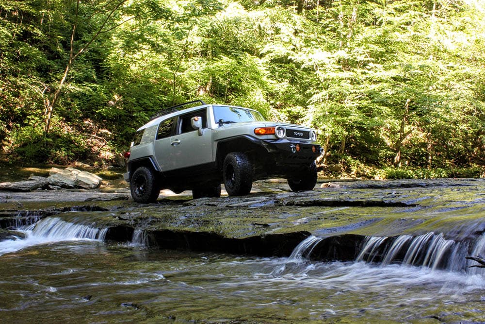 white toyota fj cruiser crossing a river