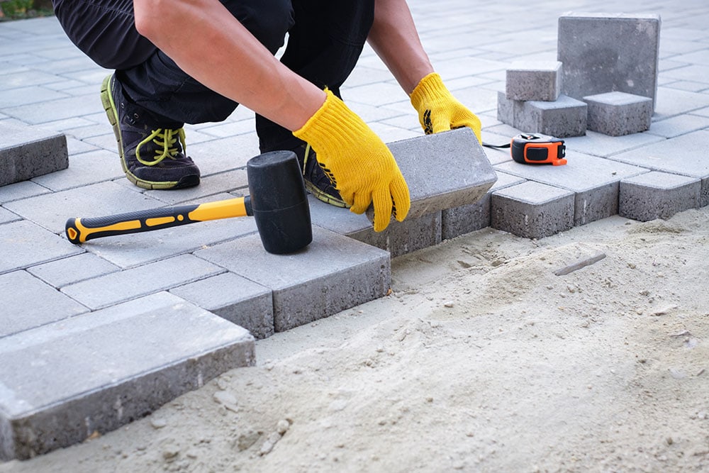 close up person installing paving stones in patio