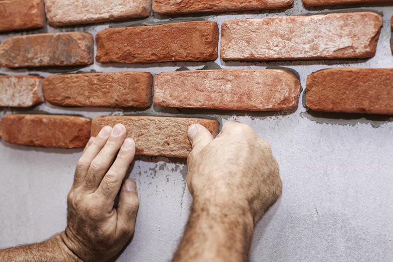 cropped bricklayer working on brick veneers