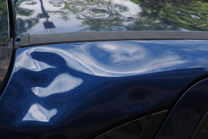 dent in a blue car's body