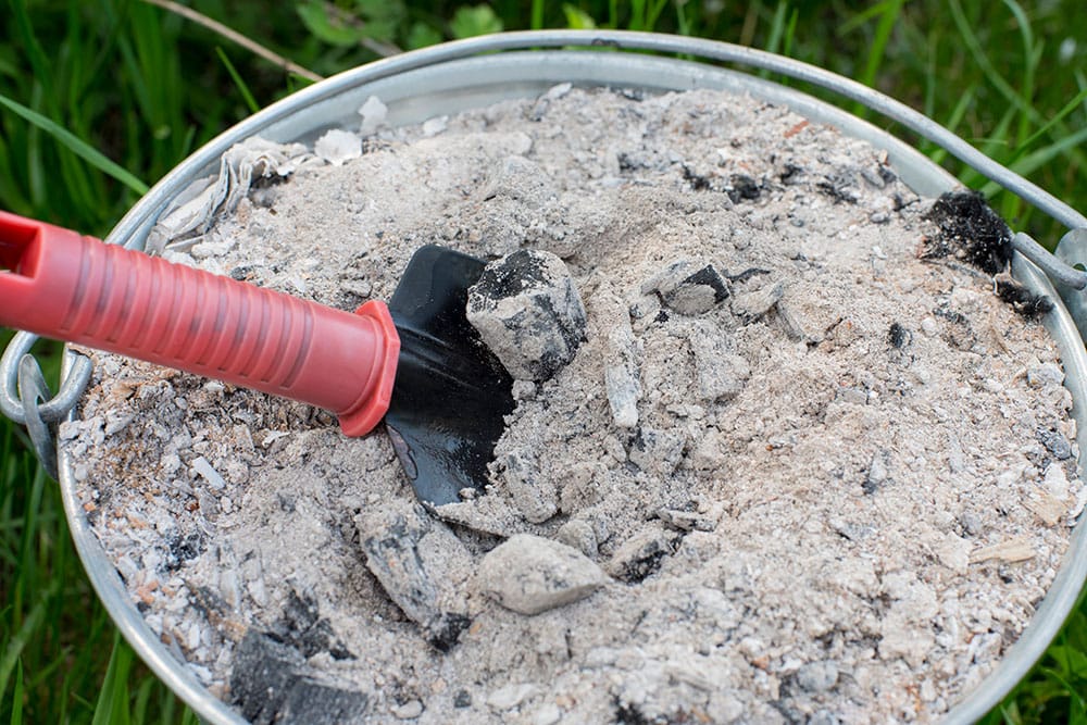 Garden shovel in a container filled with ash