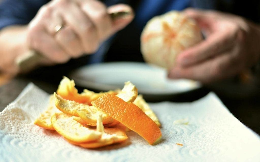 man peeling off orange